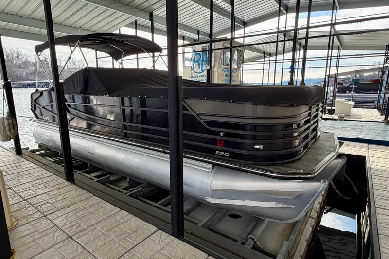 Slide: The Image of 2019 Crest Continental 250 SLS pontoon boat docked under a covered marina. - 6