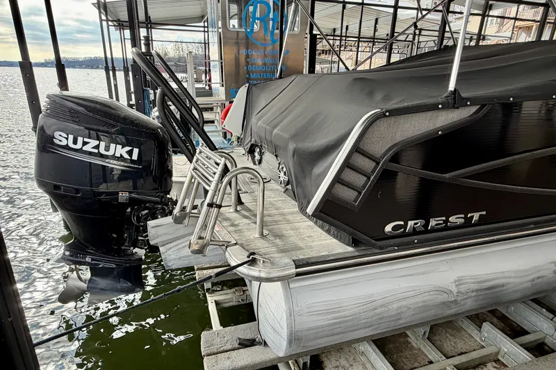 Slide: The Image of 2019 Crest Continental 250 SLS pontoon boat docked under a covered marina. - 7