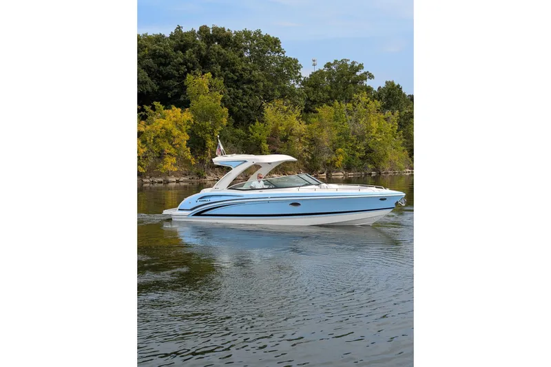 Slide: The Image of 2025 Formula 310 Bowrider I/O cruising on a calm lake with lush green trees. - 10