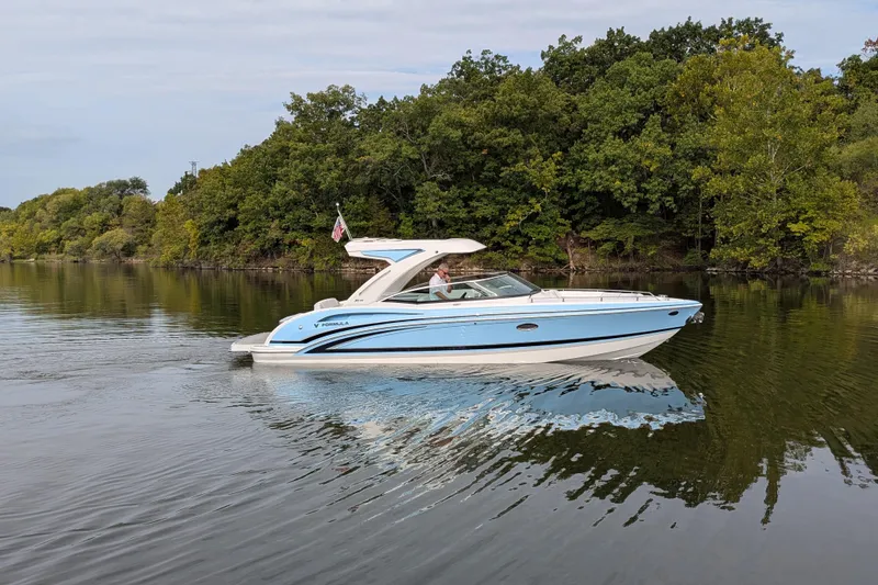 Slide: The Image of 2025 Formula 310 Bowrider I/O cruising on a serene lake with lush green trees. - 13