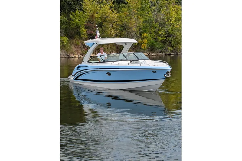 Slide: The Image of 2025 Formula 310 Bowrider I/O cruising on a serene lake with lush greenery. - 2