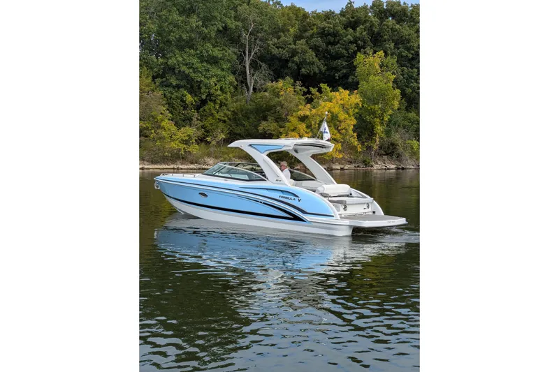 Slide: The Image of 2025 Formula 310 Bowrider I/O boat cruising on a calm lake near a forested shoreline. - 4