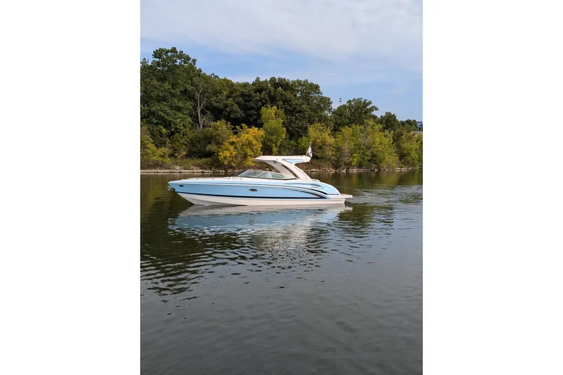 Slide: The Image of 2025 Formula 310 Bowrider I/O cruising on a calm lake with lush green shoreline. - 5