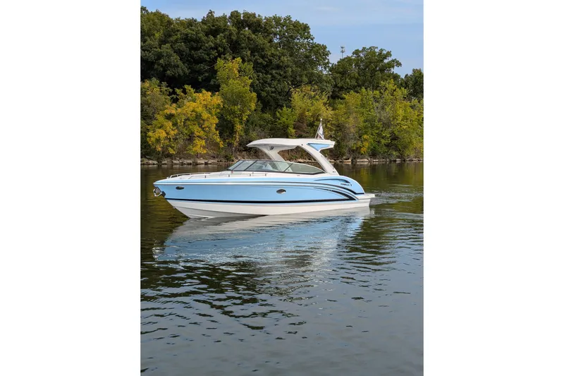 Slide: The Image of 2025 Formula 310 Bowrider I/O boat cruising on a serene lake with lush greenery. - 6