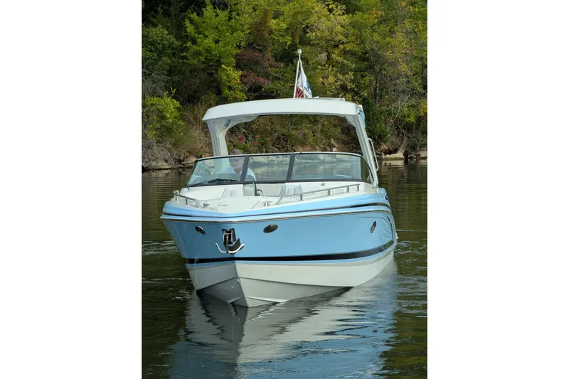 Slide: The Image of 2025 Formula 310 Bowrider I/O boat on calm water, surrounded by lush greenery. - 7