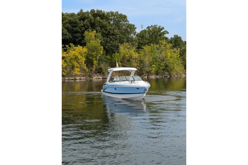 Slide: The Image of 2025 Formula 310 Bowrider I/O cruising on a serene lake with lush green trees. - 8