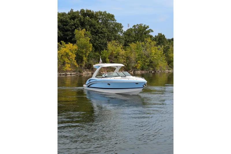 Slide: The Image of 2025 Formula 310 Bowrider I/O cruising on a serene lake with lush greenery. - 9