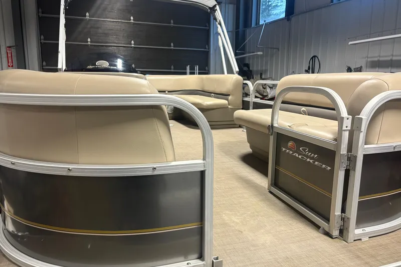 Slide: The Image of 2020 Sun Tracker Party Barge 18 DLX interior with beige seating in a garage setting. - 3