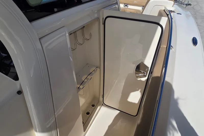 Slide: The Image of 2021 Scout 305 LXF boat storage compartment with open door and hooks. - 18