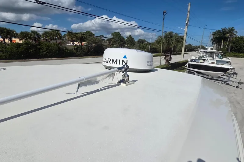 Slide: The Image of 2021 Scout 305 LXF boat with Garmin radar, parked outdoors under a clear blue sky. - 21