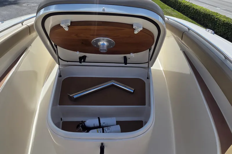 Slide: The Image of Open storage compartment on 2021 Scout 305 LXF boat, featuring fire extinguishers and metal parts. - 26