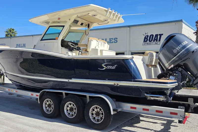 Slide: The Image of 2021 Scout 305 LXF boat on trailer, featuring Yamaha outboard motor, parked at dealership. - 3