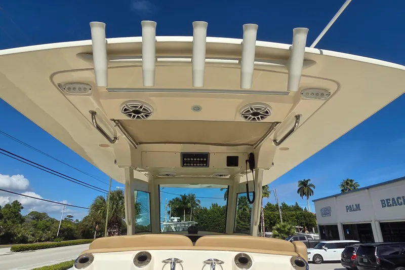 Slide: The Image of 2021 Scout 305 LXF boat with rod holders and speakers, parked outdoors under clear blue sky. - 30