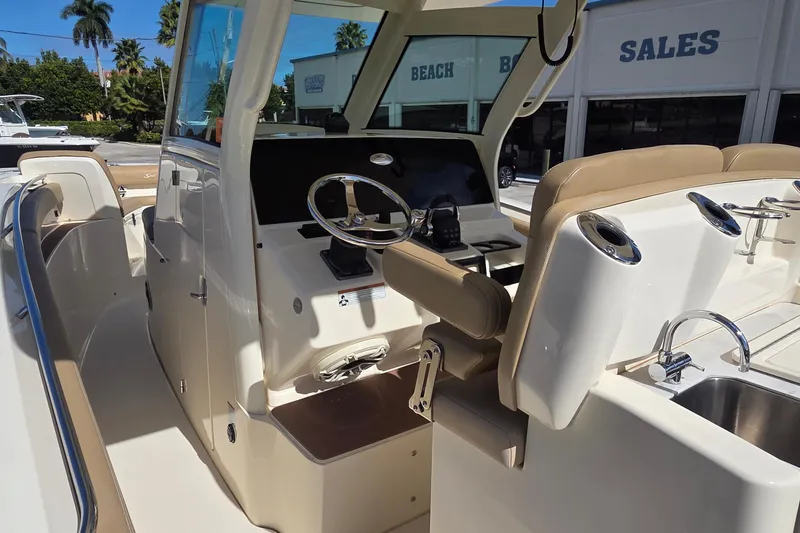 Slide: The Image of 2021 Scout 305 LXF boat interior with helm, seating, and sink in a sales showroom. - 5