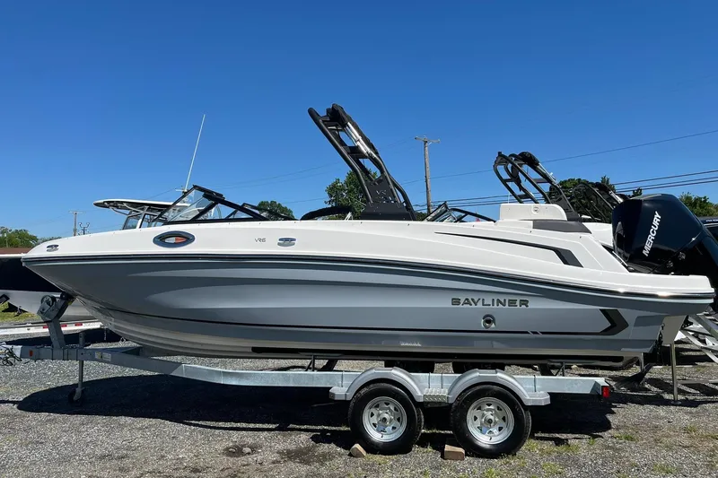 The Image of 2026 Bayliner VR6 Bowrider OB on trailer, sleek design, outboard motor, clear blue sky. - 2