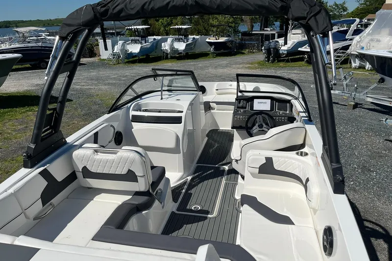 Slide: The Image of 2026 Bayliner VR6 Bowrider OB interior with seating and steering console, docked outdoors. - 8