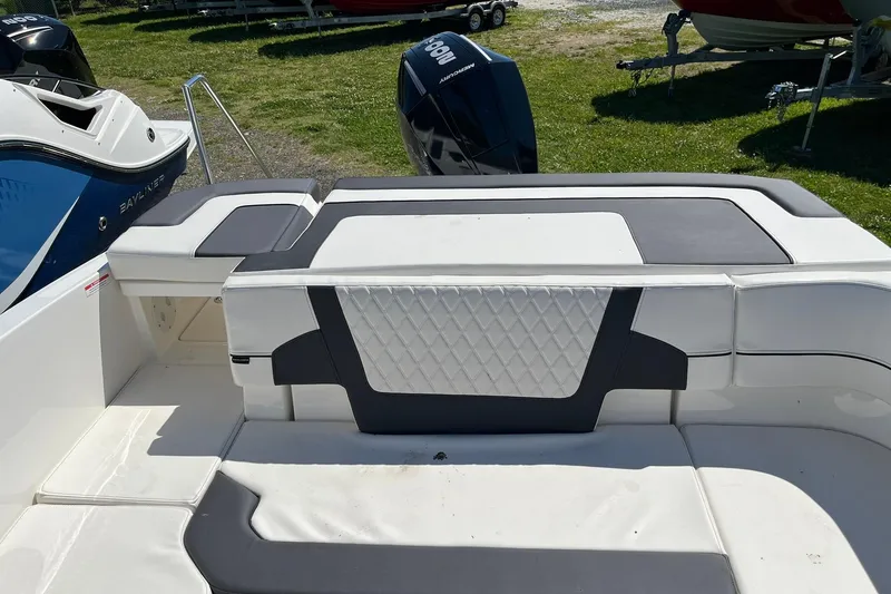 Slide: The Image of 2026 Bayliner VR6 Bowrider OB boat interior with cushioned seating and outboard motor. - 9