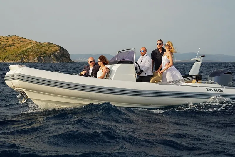Slide: The Image of 2026 Brig Eagle 6.7 boat cruising with passengers on a scenic ocean backdrop. - 6