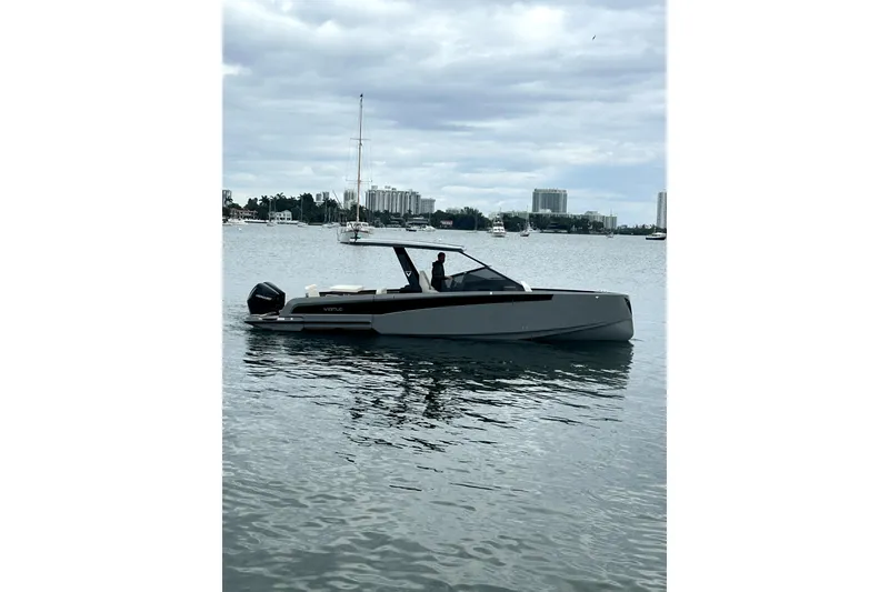 Slide: The Image of A 2026 Virtue V10 boat on a calm waterway with cityscape background. - 130