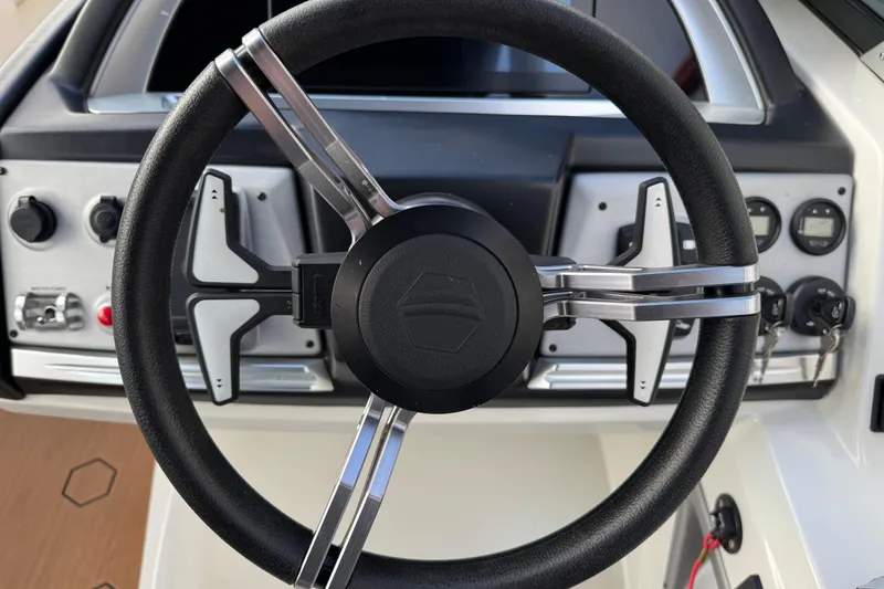 Slide: The Image of Steering wheel of 2022 South Bay 25 Sport RS9-DC boat, featuring modern dashboard controls. - 23