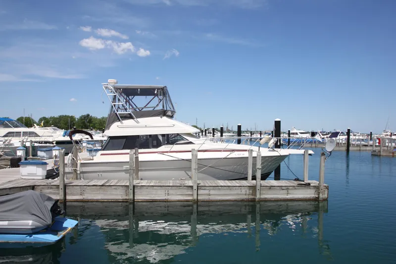 Slide: The Image of 1990 Silverton 34 Convertible yacht docked in a marina under a clear blue sky. - 2