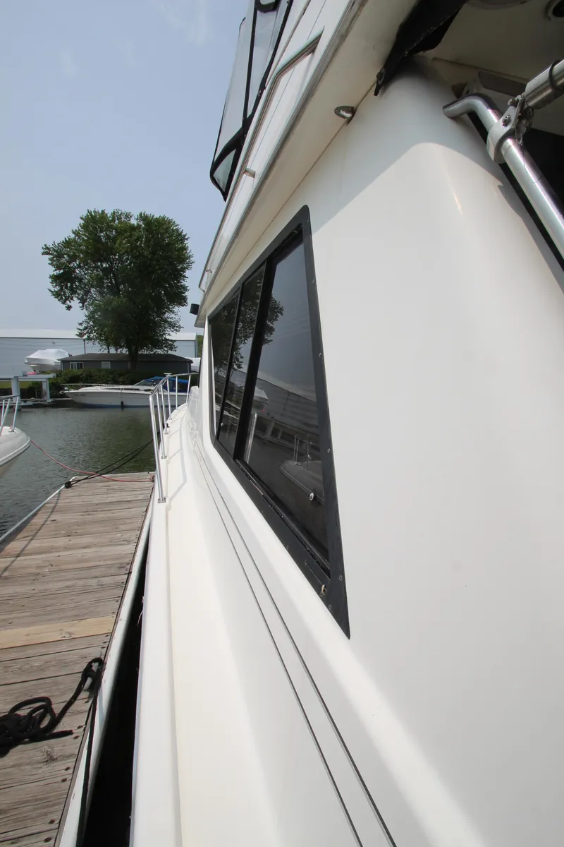 Slide: The Image of 1996 Bayliner 3988 Command Bridge Motoryacht docked, side view with windows and railing. - 4