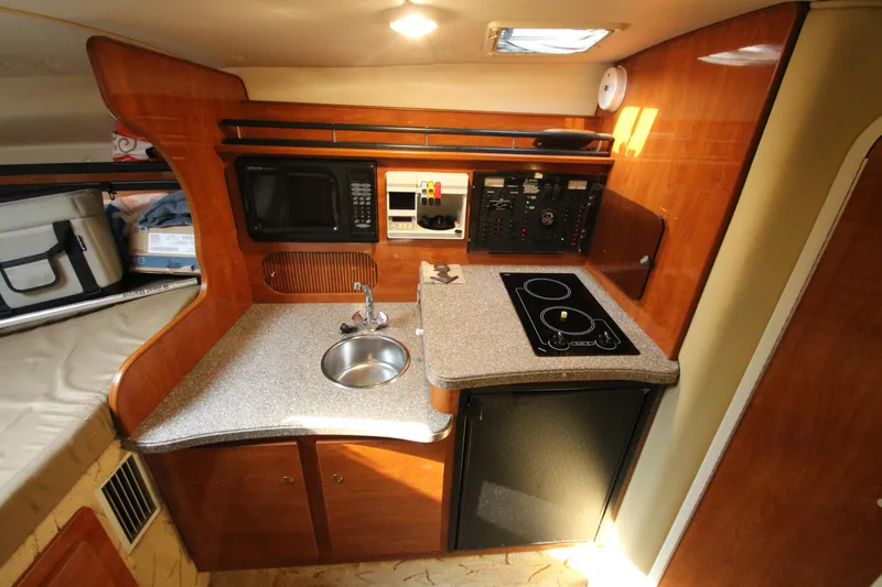 Slide: The Image of 2005 Rinker 312 Fiesta Vee boat interior kitchen with sink, stove, and microwave. - 33