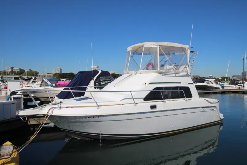 The Image of 1995 Mainship 31 Sedan Bridge boat docked in marina under clear blue sky. - 0