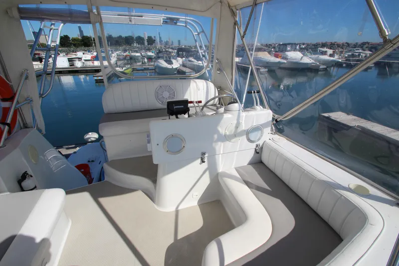 Slide: The Image of 1995 Mainship 31 Sedan Bridge interior with helm, seating, and marina view. - 10