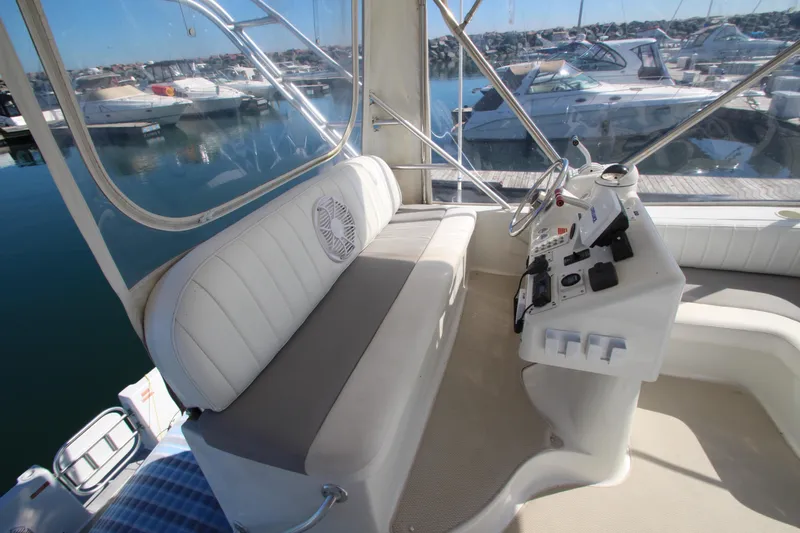 Slide: The Image of 1995 Mainship 31 Sedan Bridge helm with white seating and marina view. - 11