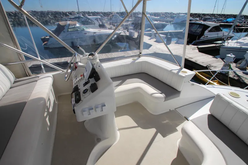Slide: The Image of 1995 Mainship 31 Sedan Bridge interior with helm and seating, docked at marina. - 12
