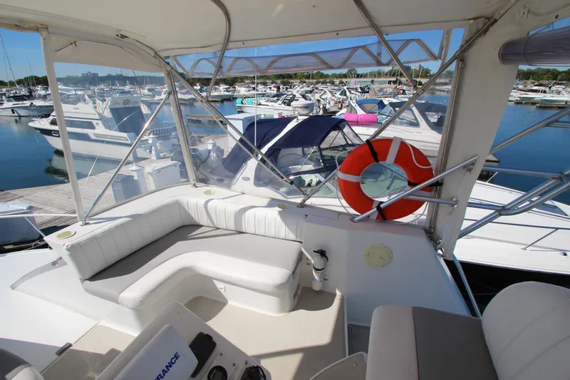 Slide: The Image of 1995 Mainship 31 Sedan Bridge interior with marina view, featuring seating and life preserver. - 14