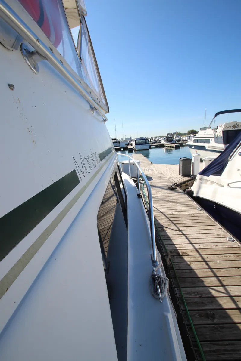 Slide: The Image of 1995 Mainship 31 Sedan Bridge docked at marina under clear blue sky. - 23
