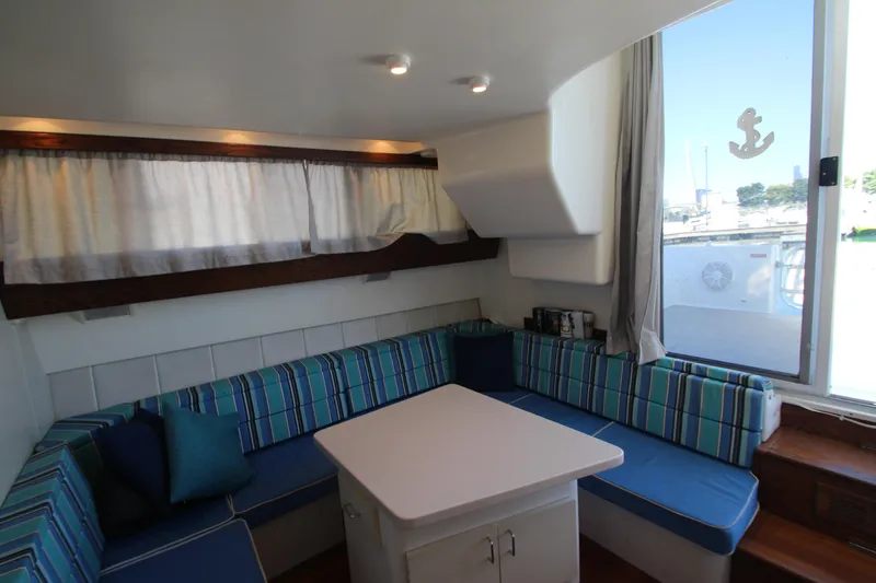 Slide: The Image of Cozy interior of 1995 Mainship 31 Sedan Bridge with striped seating and table. - 28