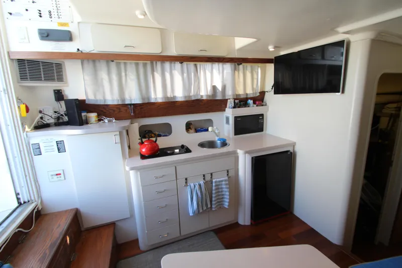 Slide: The Image of 1995 Mainship 31 Sedan Bridge interior kitchen with stove, fridge, and TV. - 31