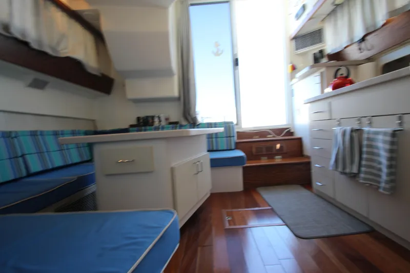 Slide: The Image of Interior of 1995 Mainship 31 Sedan Bridge with blue seating and wooden flooring. - 36