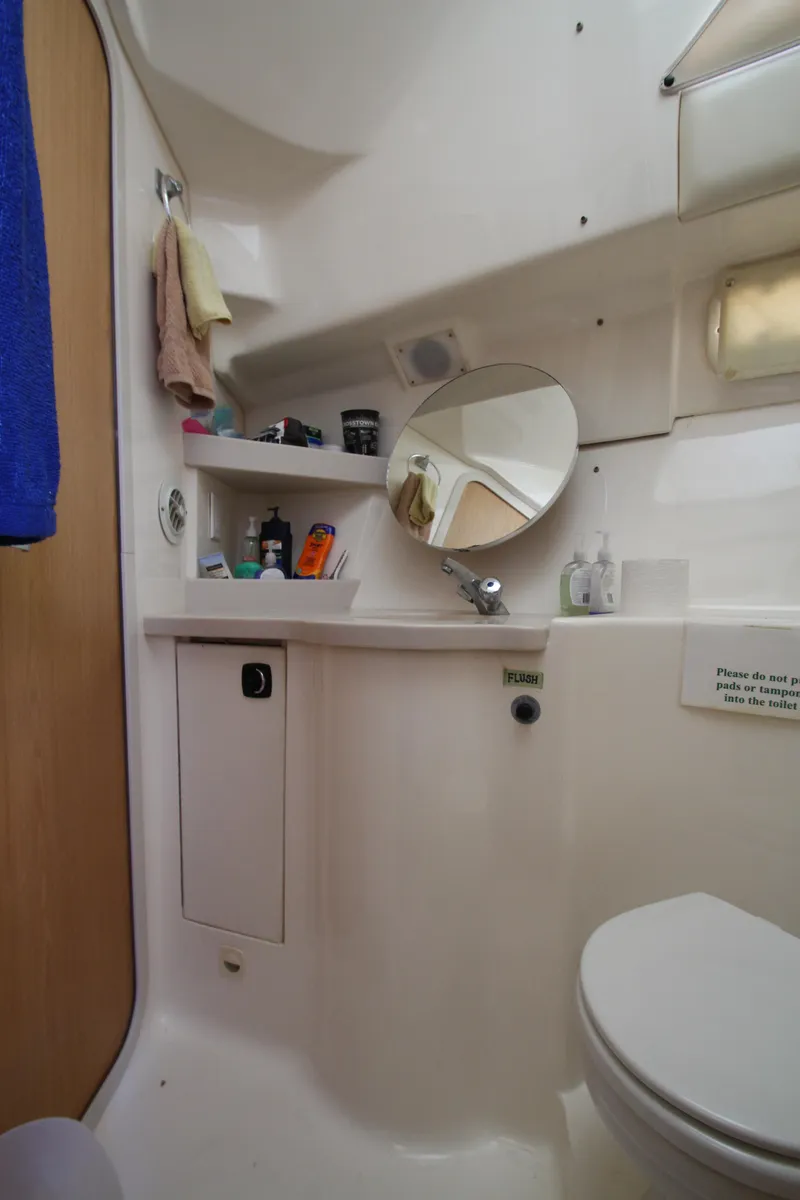 Slide: The Image of 1995 Mainship 31 Sedan Bridge bathroom with mirror, sink, and storage shelves. - 39