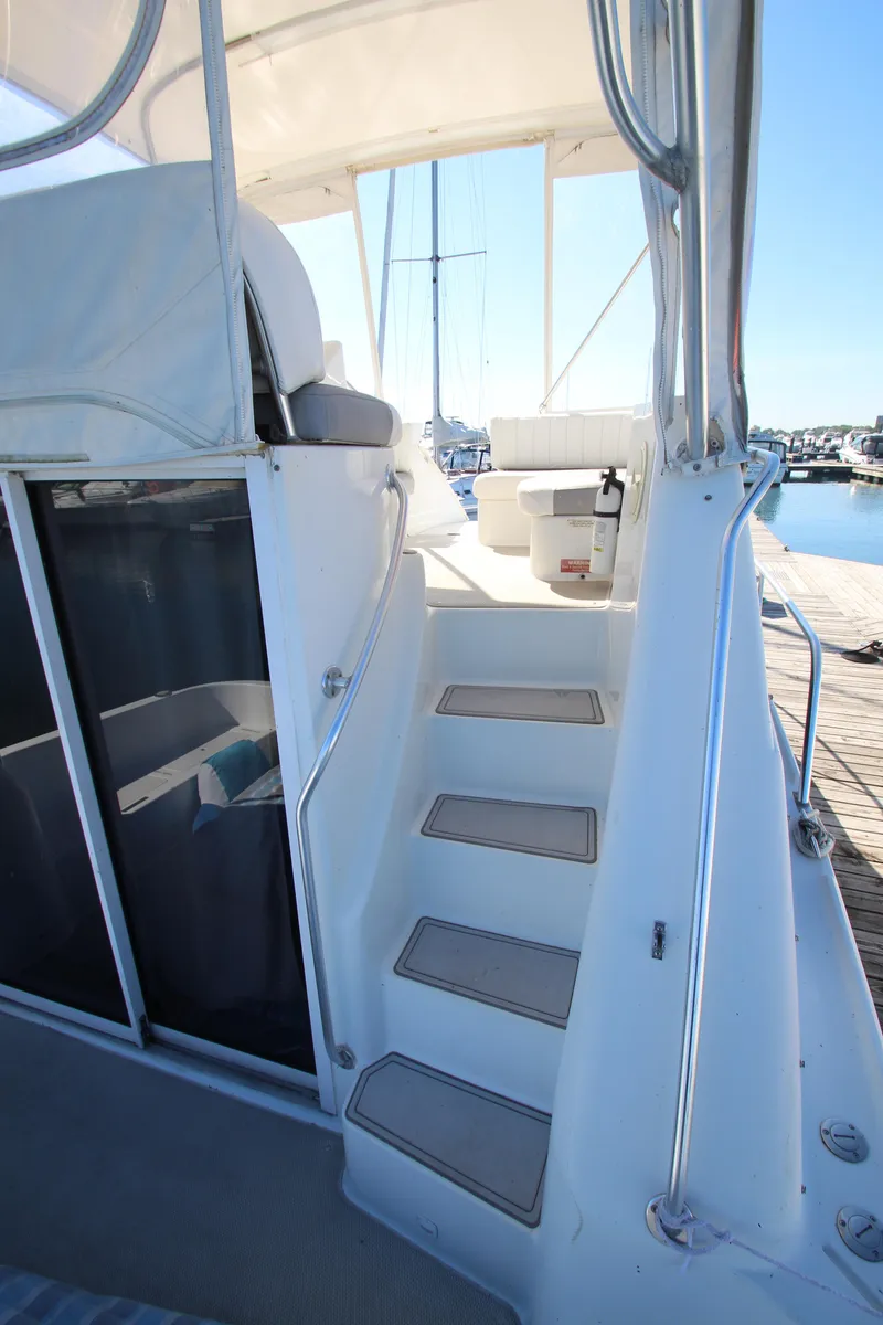 Slide: The Image of 1995 Mainship 31 Sedan Bridge yacht with steps leading to upper deck, docked at marina. - 4