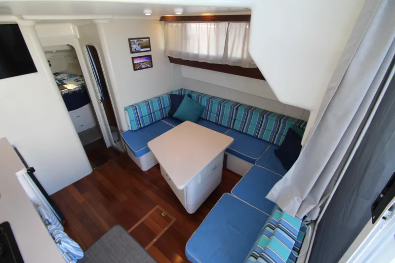 Slide: The Image of 1995 Mainship 31 Sedan Bridge interior with blue-striped seating and wooden flooring. - 46
