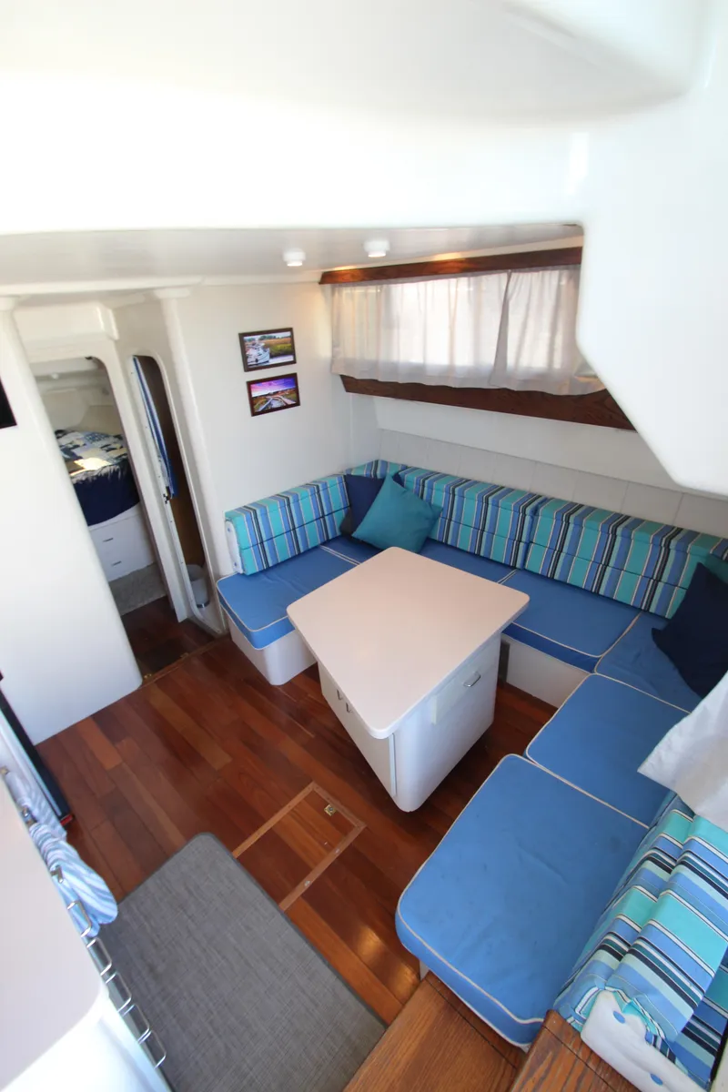 Slide: The Image of 1995 Mainship 31 Sedan Bridge interior with blue-striped seating and wooden flooring. - 47