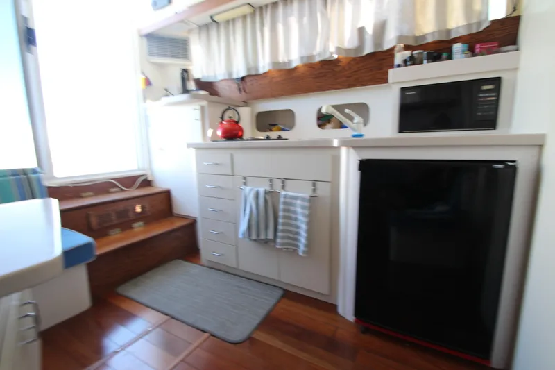 Slide: The Image of Interior of 1995 Mainship 31 Sedan Bridge with kitchenette, fridge, and wooden flooring. - 49