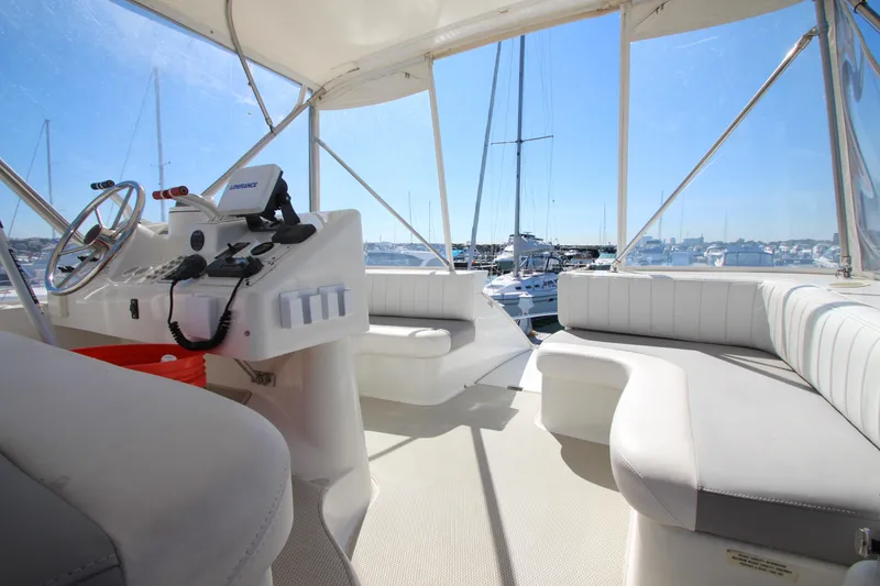 Slide: The Image of 1995 Mainship 31 Sedan Bridge interior with helm and seating, overlooking marina. - 6