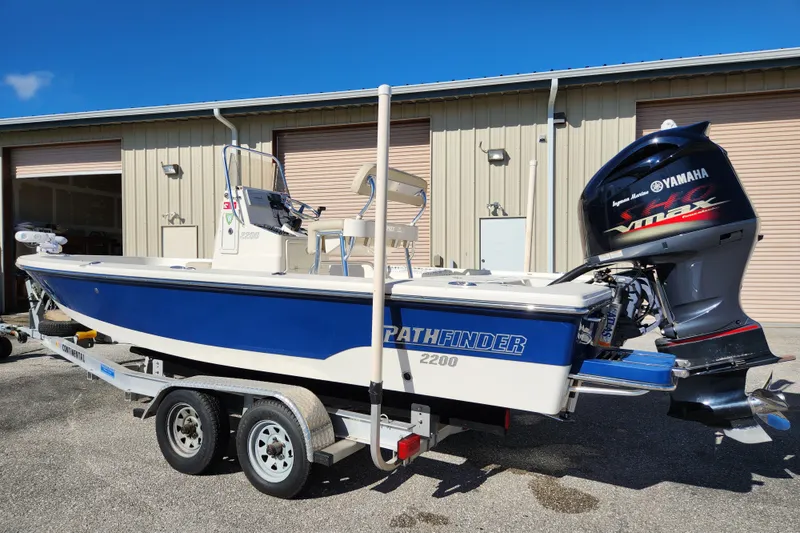 Slide: The Image of 2014 Pathfinder 2200 TRS boat with Yamaha engine on trailer, parked outside a building. - 1