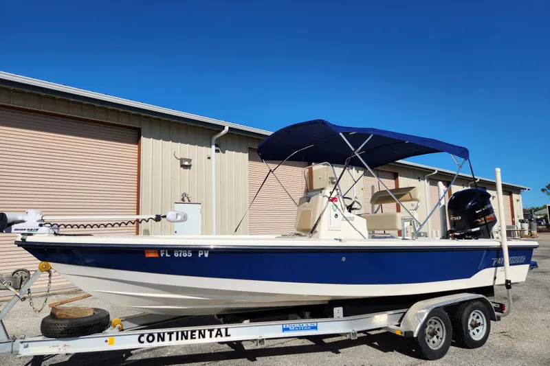 Slide: The Image of 2014 Pathfinder 2200 TRS boat on trailer, blue and white, parked near a building. - 6