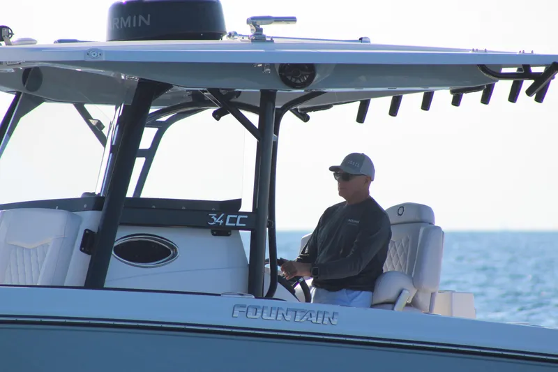 Slide: The Image of 2025 Fountain 34 Center Console boat on water, person steering, sunny day. - 5
