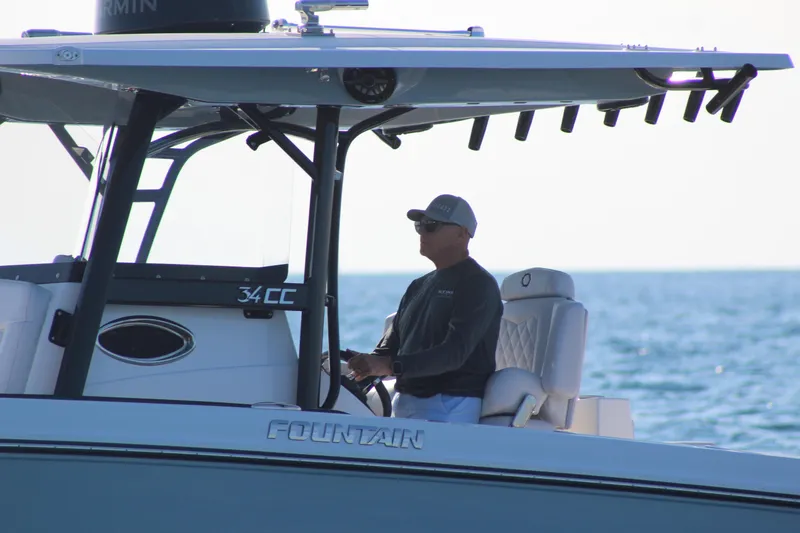 Slide: The Image of 2025 Fountain 34 Center Console boat on water, person steering, sunny day. - 6