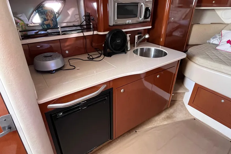 Slide: The Image of 2008 Sea Ray 330 Sundancer cabin with kitchenette, featuring sink, microwave, and compact fridge. - 26