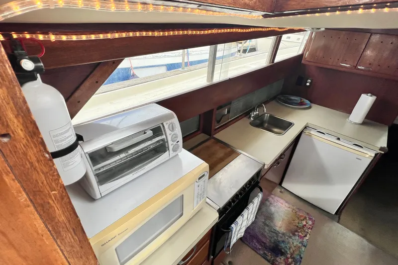 Slide: The Image of 1967 Chris-Craft 38 Constellation kitchen with appliances, sink, and wooden cabinetry. - 22