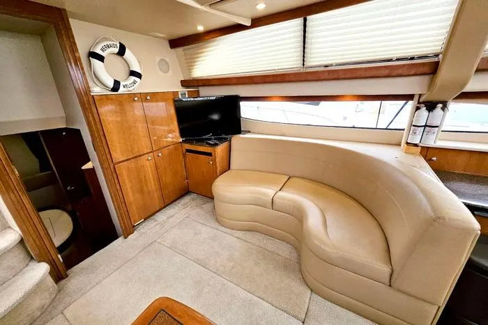 Slide: The Image of 2006 Meridian 368 Motoryacht interior with curved seating, TV, and wooden cabinetry. - 11