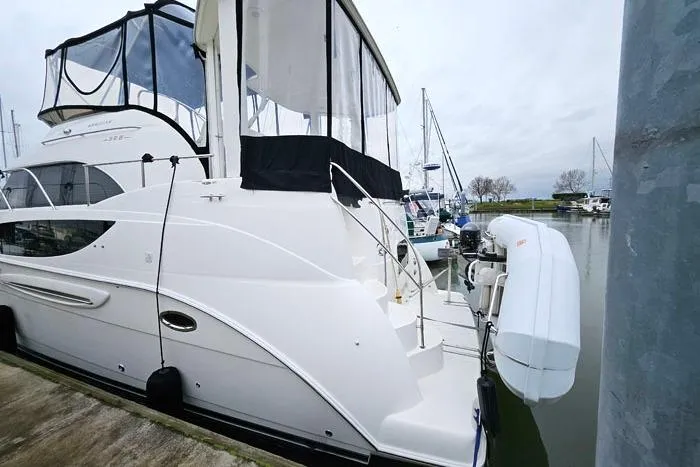 Slide: The Image of 2006 Meridian 368 Motoryacht docked at marina, featuring sleek white design and covered upper deck. - 3